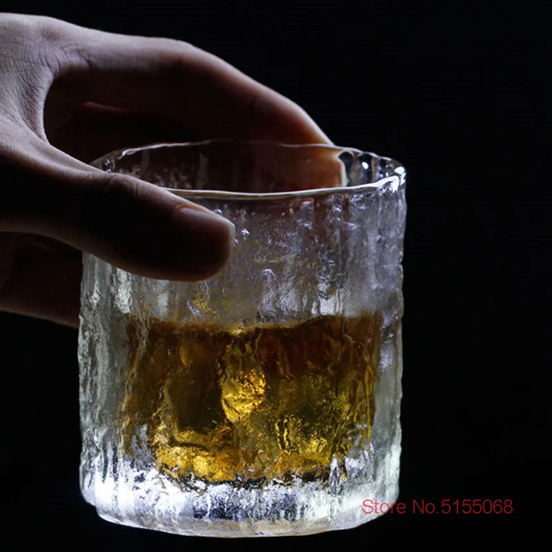 Une main qui tient le verre à whisky